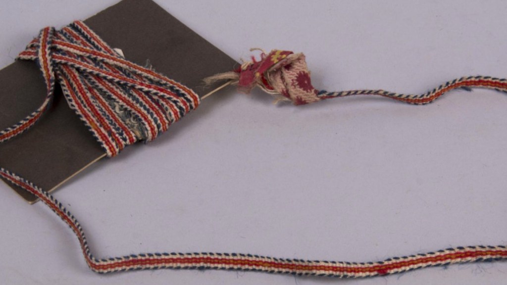 Alkuperäinen pirtanauha Kunstkamerassa. Nauhan päässä kangastertut.