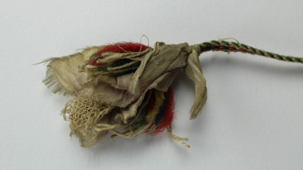 Karjalaisen pirtanauhan terttupää, jossa harsokangasta ja silkkiä sekä muita kankaita.