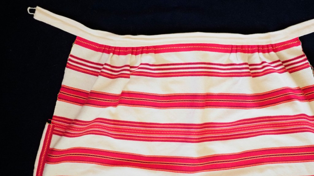 Itse kudotun esiliinan yläosa.