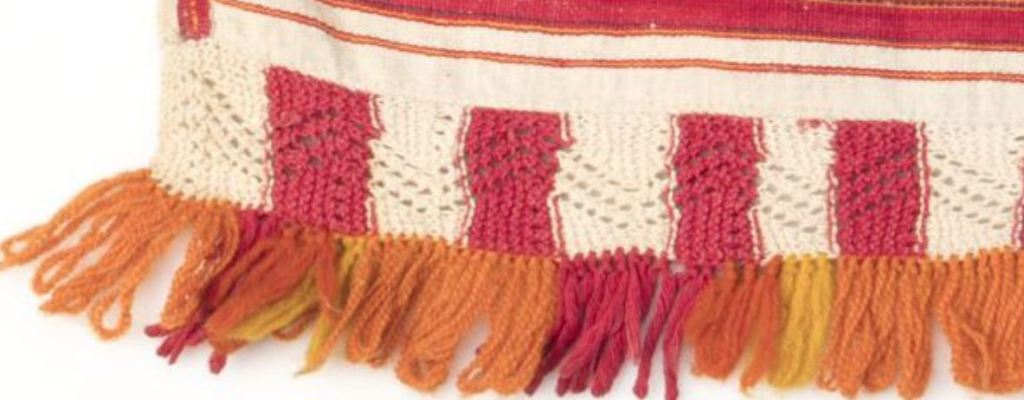 Historiallisen esiliinan helmaa, jossa leivonpääsolmuilla kiinnitettyjä lankalenkkejä.