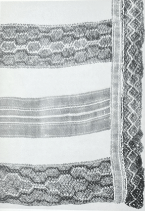 Mustavalkokuva esiliinan nyytingistä, jossa monimutkainen koristekuvio.