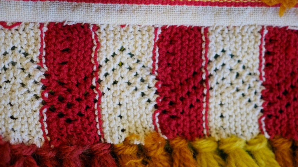 Värikäs esiliinan helmapitsi Jääsken kihlakunnan kudonnaisesiliinaan.