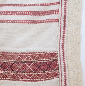 Lähikuva Jääsken kihlakunann esiliinasta, jossa nyytingit ovat punaisia .