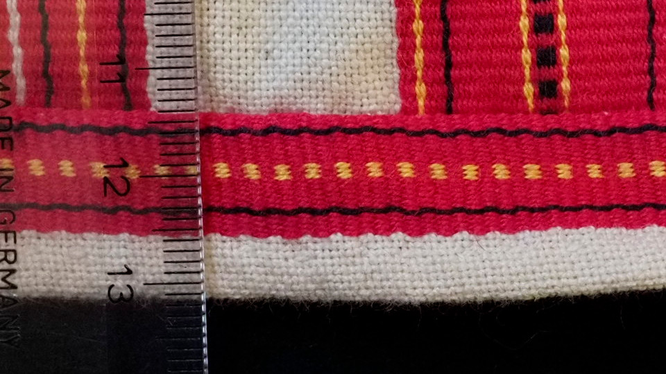 Jääsken kihlakunnan kudonnaisesiliinan ripsiraitoja lähikuvassa, reunaraita.