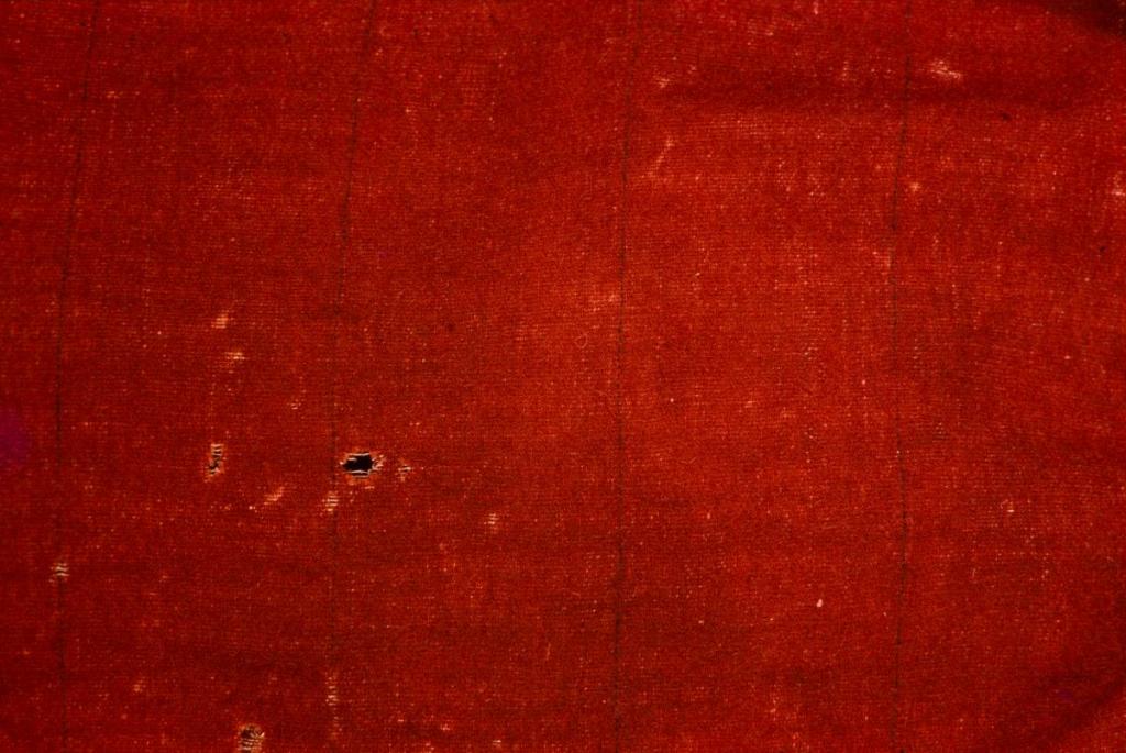 Lähikuva punaisesta puolivillaisesta körttikankaasta, jossa kulkee säännöllisin välein musta raita.