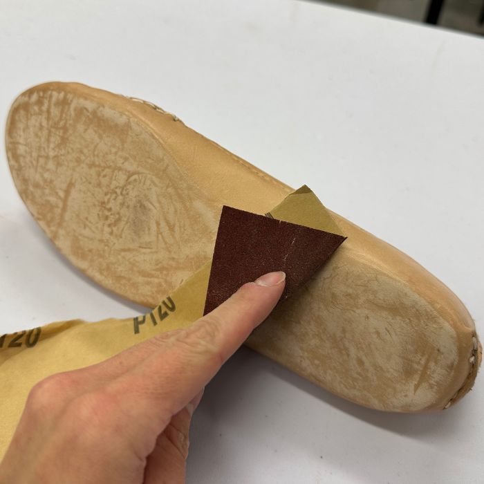 Kengän pohjaa hiotaan hiomapaperilla.